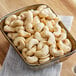 A bowl of medium raw cashews on a wooden table.