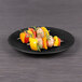An Elite Global Solutions Hermosa matte black melamine plate with food on it.