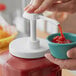 A hand pouring ketchup into a bowl using a Choice threaded adapter lid.