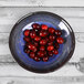 A cobalt blue Elite Global Solutions melamine bowl filled with cranberries on a table.