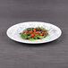 A black marble embossed Elite Global Solutions melamine plate with a salad on it.