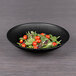 A matte black Elite Global Solutions melamine bowl filled with salad, tomatoes, and spinach.