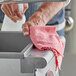 A person cleaning a stainless steel sink with a red Unger MicroWipe Pro towel.