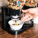 A hand pouring cereal from a Zevro double dry food dispenser into a bowl.