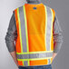 A person wearing an Ergodyne orange reflective surveyor vest.