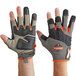 A close-up of a pair of Ergodyne heavy-duty framing gloves with orange and black accents on a pair of hands.