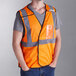A person wearing an Ergodyne orange high visibility mesh vest with an ID holder.