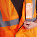 An orange Ergodyne high visibility mesh vest with reflective tape and an ID holder.