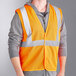 A man wearing an Ergodyne orange reflective mesh vest.