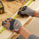 A person wearing Ergodyne ProFlex heavy-duty work gloves measures a piece of wood with a measuring tape.