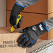A person wearing Ergodyne ProFlex thermal work gloves cutting a box with a yellow tool.