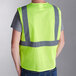 A person wearing a lime yellow Ergodyne high visibility mesh vest with reflective stripes.