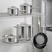 A stainless steel rack with Vollrath Optio stainless steel cookware set pots and pans.