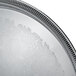 A close-up of a stainless steel Vollrath round catering tray with intricate designs.