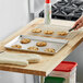 A person placing cookies on a Baker's Mark wire-in-rim sheet pan on a table.