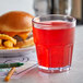 A clear plastic GET Bahama tumbler filled with red liquid next to a hamburger and fries.
