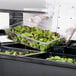 A chef using a Carlisle Maximizer Portable Salad Bar to prepare a large container of salad.