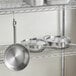 A metal rack with Vigor stainless steel pots and pans.