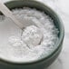 A spoonful of white powder in a bowl.