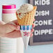 A hand holding a JOY waffle cone with ice cream inside.