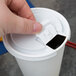 A hand opening a Solo white plastic cup lid.