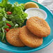A plate of Mrs. Friday's breaded Krabbycakes with a side of salad and a lemon.