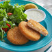 A plate of Mrs. Friday's Original Breaded Krabbycakes with salad and a lemon slice.