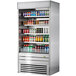 A Turbo Air stainless steel vertical air curtain display case full of drinks on shelves.