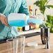 A person pouring blue liquid into a plastic container using a Choice pour bottle.