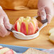 An OXO Good Grips stainless steel apple corer/slicer cutting a pink apple.