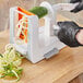 A person using the OXO Good Grips Tabletop Spiralizer to cut zucchini.
