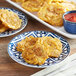 A white plate of White Toque Fried Plantain Tostones with a bowl of red sauce.