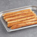 A tray of White Toque prefried plain churros on a gray surface.
