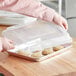 A person using a Baker's Mark polypropylene bun / sheet pan cover to take cookies off a tray.