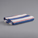 A folded Monarch Brands pool towel with navy and red stripes on a gray surface.