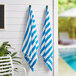 Two Monarch Brands blue and white striped pool towels hanging on a wall.