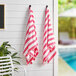 Two Monarch Brands Cali Cabana pink and white striped pool towels hanging on a wall.