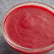 A bowl of Les Vergers Boiron red raspberry puree on a white background.