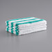 A stack of Monarch Brands green striped pool towels on a gray surface.