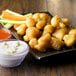 A plate of Fred's Battered Cauliflower nuggets with dip and vegetables.