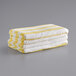 A stack of yellow and white Monarch Brands California Cabana pool towels.