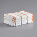 A stack of white towels with orange stripes.