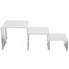 American Metalcraft stainless steel display riser set on a white rectangular table with metal legs.