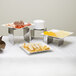 A table with American Metalcraft stainless steel risers holding plates of food.