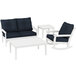 A white POLYWOOD patio set with blue and black cushions, including a blue couch, white table, and white rocking chair.