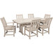 A POLYWOOD sand dining table with six white chairs on an outdoor patio.