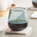 An Acopa blue stemless wine glass with dark liquid on a coaster.