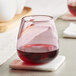 A Mauve Acopa stemless wine glass filled with red wine sits on a coaster.