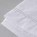 A close up of a white Oxford Superblend microfiber flat sheet with gold stitching.