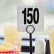 American Metalcraft plastic table number cards 101 to 150 on a table with a drink.